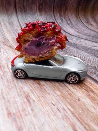 cut piece of berry eclair on toy car on wooden futage, order and delivery concept with copy spaceの写真素材