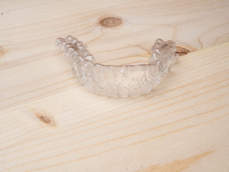 Inivisalign braces. Invisible aligner on wooden surface