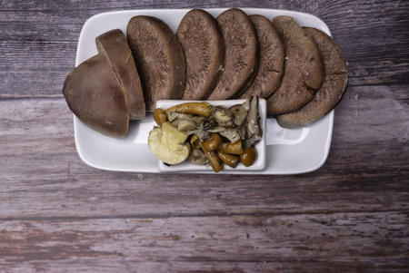 Boiled beef, pork tongue with champignon and other mushrooms, studio shot, isolated on wood background. Top viewの写真素材
