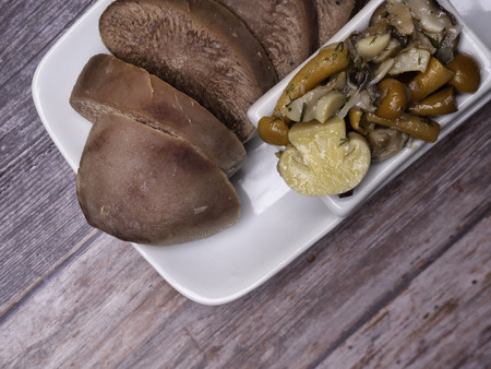 Boiled beef, pork tongue with champignon and other mushrooms, studio shot, isolated on wood background. Top viewの写真素材