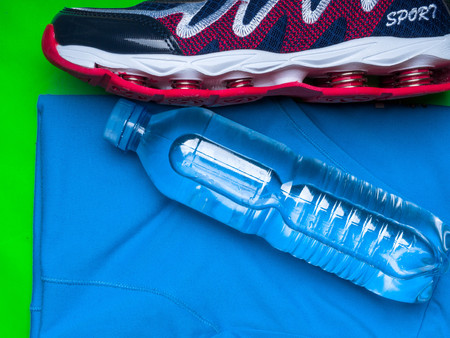 Sports runner shoe, shirt and a bottle of water on green sport mat, copy spaceの写真素材