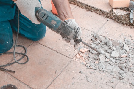 Men in work cloth worker are extracting tiles with perforator because tiling wrong.の写真素材