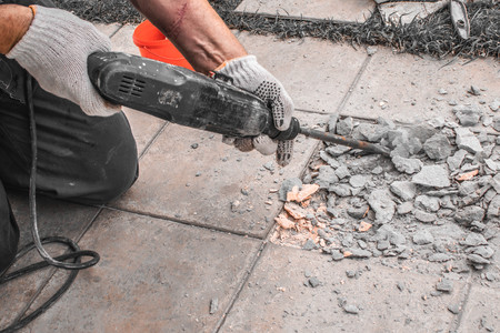 Men in work cloth worker are extracting tiles with perforator because tiling wrong.の写真素材