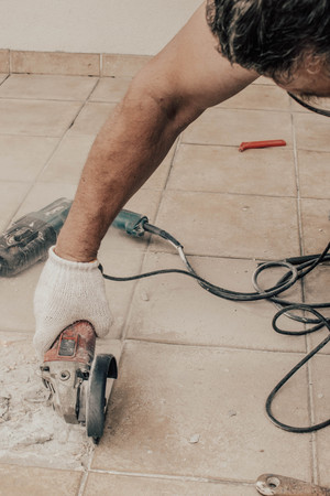 A circular saw. A man sawing ceramic tiles. Worker sawing a tile on a circular saw. Construction...