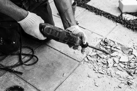 Professional builder man in dusty uniform, tile and perforator. Concept overhaul, renovation, redevelopmentの写真素材