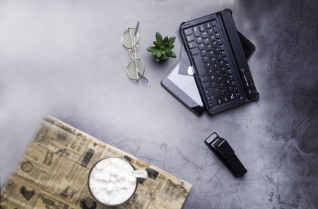 office table, coffee, glasses, stapler, cactus, laptop, credit card on concrete table with...