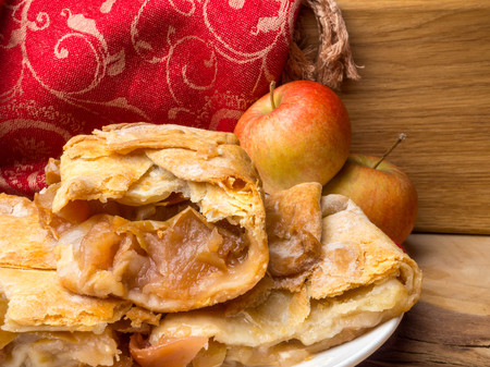 Slices of mouth watering rustic apple pie, homemade with decoration on wooden backgroundの写真素材