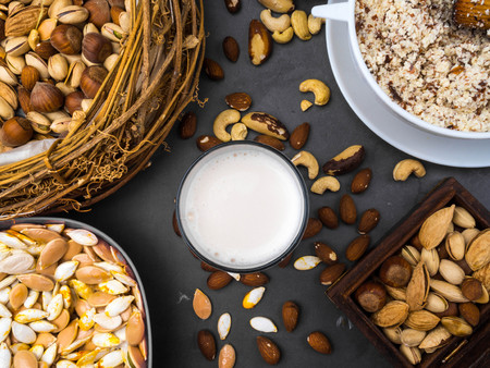 Vegan milk from nuts in glass with various nuts. Organic healthy snack vegan vegetarian, with copy...