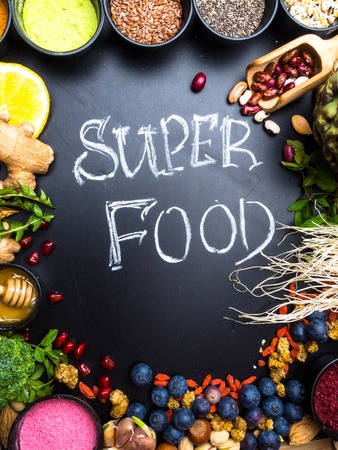 Super food or vegetarian food concept. Seeds, cereals, beans, vegetables, herbs for healthy cooking on black wooden background top view with copy spaceの写真素材