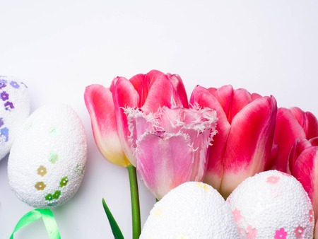 Easter eggs with tulips on a white surface, with copy spaceの写真素材