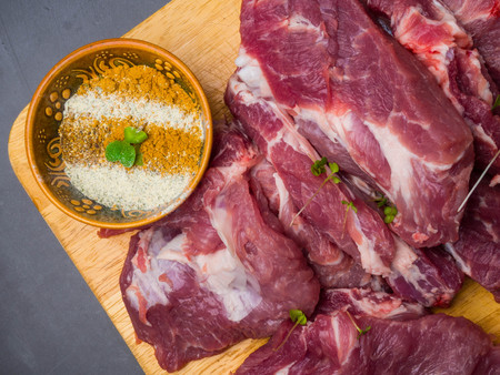fresh pork with ingredients for cooking on dark concrete background