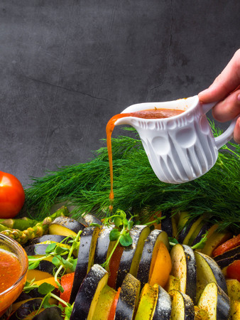 raw vegetables, Ratatouille - traditional French Provencal vegetable dish cooked in oven, vegetarian food, health food concept, pours red sauceの写真素材