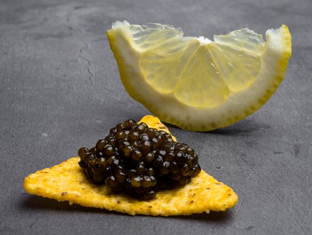 Black caviar and lemon slice on grey background, top view with copy space at the side. suitable for restaurant menu template.の写真素材