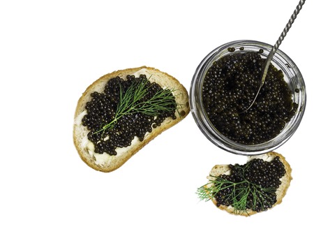 Sandwiches with black caviar, a jar of caviar and a spoon. On a wooden table, with dillの写真素材