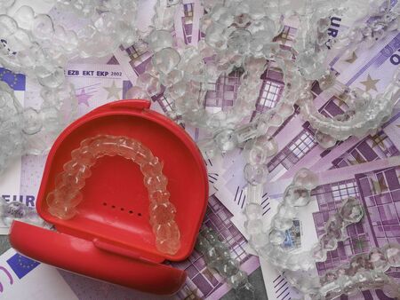 teeth braces or retainer in container isolated on cash money, costs concept