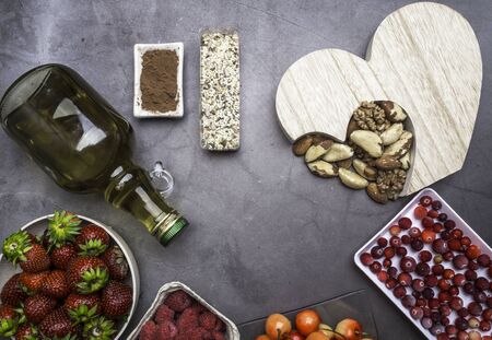 Healthy diet for the cardiovascular system with a wooden heart, seeds, berries, nuts , oil copy spaceの写真素材