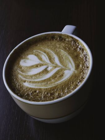 Cup of cappuccino with latte art heart shape wooden background