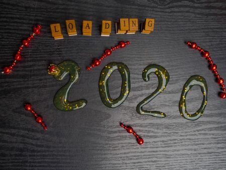 Loading for new 2020 year on wooden board, with text inscription, red garland, copy spaceの写真素材