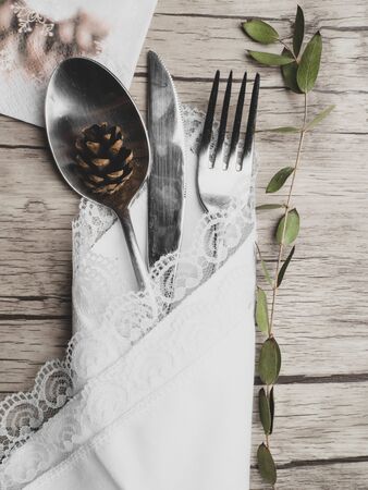 Christmas menu concept . Flat lay with Xmas decorations, green branch and cone, silver fork knife spoon set with white ruffled napkin. Copy spaceの写真素材