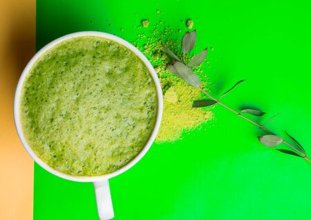 Green matcha tea latte drink and powder on green background. Japanese tea ceremony concept. Copy...