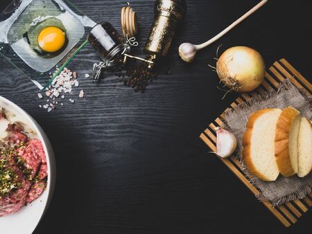 Preparing meatball with ingredients, such as egg, meat, bread, onion, garlic, herbs on wooden board, copy space, top viewの写真素材