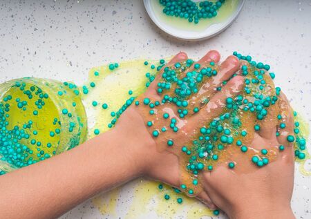 Kid Playing Hand Made Toy Called Slime on white table
