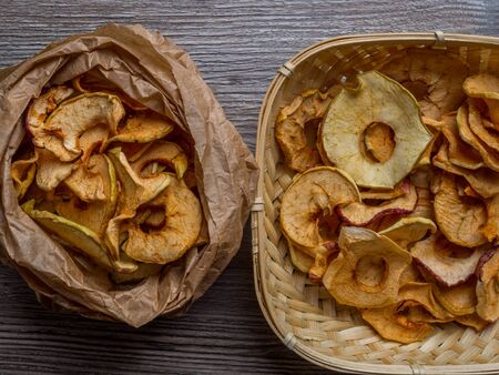 Homemade sun-dried organic apple slices, crispy apple chips, on wooden background and fresh apple....