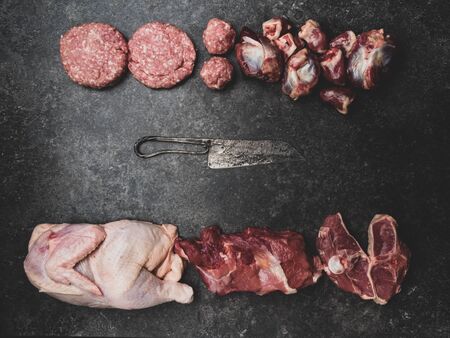Different mixed types of raw fresh meat on cutting board with knifeの写真素材