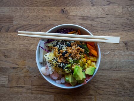 Ahi tuna and shrimps poke bowl meal horizontal view. Poke is a traditional Hawaiian dish influenced...