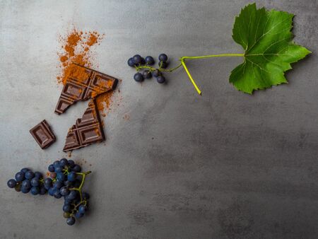 Fresh ripe grape, and dark chocolate on concrete background. Food rich in resveratrol, antioxidants,...