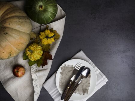 Festive Thanksgiving Day food background with pumpkin, color leaves, cutlery on dark rustic kitchen table, top view, copy spaceの写真素材