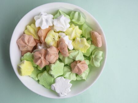 Ceramic vase full of colorful, yellow, white, pink, green merengues at pastel mint backgroundの写真素材