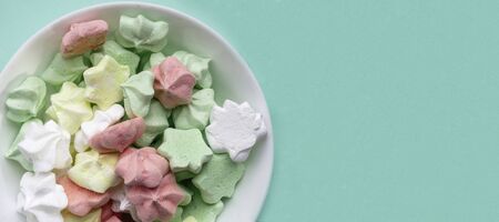 Ceramic vase full of colorful, yellow, white, pink, green merengues at pastel mint backgroundの写真素材