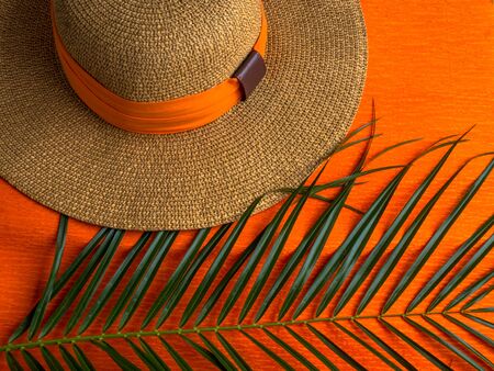 Summer background. Vacation, holiday, travel, tourism concept. Hat, tropical palm leaves on orange background. Top view. Copy spaceの写真素材