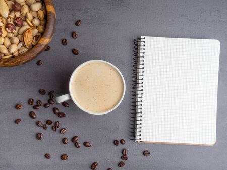 breaking time in office, fresh coffee, mix of nuts for brain, and white notepad for notes. Minimalist style on a grey desk background.の写真素材