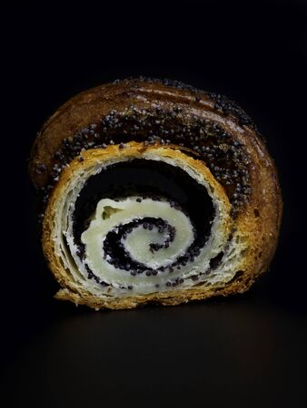 Sweet bun with poppy seeds on black background. Homemade fresh roll horn with poppy seeds.の写真素材