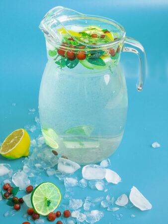 Fruit and berry lemonade drinks, refreshment infused water, in glass jars, with fresh cranberries, lemon and lime slices on blue background. Detox drinkの写真素材