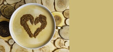 A cup of coffee on wooden table from top view. Heart shape art from cinnamon powder. Banner, copy...
