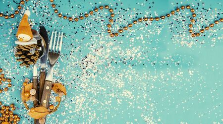 christmas table set with funny snowman in red cap, cone on trendy green mint color background with colorful confetti. Holiday concept. Bannerの写真素材
