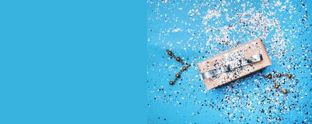 Coral color gift box with silver bow in mint background with shiny confetti. Holiday and festive backdrop. Flat lay style. Christmas, New Year, Birthday, Weeding gift Invitation card on blue surface, copy spaceの写真素材