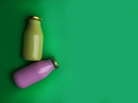 Fruit and vegetables smoothies in glass bottles on green background. Fresh organic Smoothie...