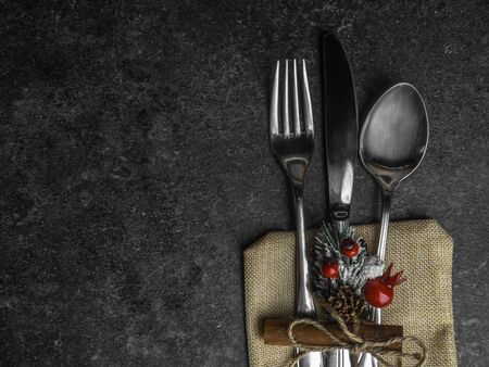 Christmas table place setting, cutlery in burlap bag with festive decorations star, cinnamon stick, pinecone with snow, berries, branch. Christmas Xmas New Year holiday background, top viewの写真素材