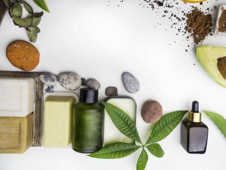 Health spa with massage oil, serum, cocoa butter, soap,coffee scrub, avocado, green leaf on white background, copy spaceの写真素材
