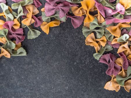 Homemade colorful Italian pasta on grey marble background. Various colors of bow tie tagliatelle,...
