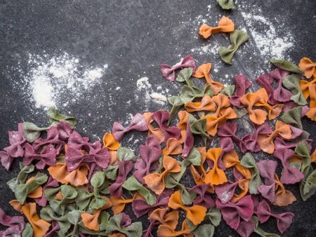 Homemade colorful Italian pasta on grey marble background. Various colors of bow tie tagliatelle, farfalle pasta. Top view. Selecive focus. Copy spaceの写真素材