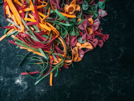 Homemade egg pasta farfalle tagliatelle tagliolini bow-tie, fettuccine colorful pasta on grey...