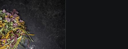 Homemade egg pasta farfalle tagliatelle tagliolini bow-tie, fettuccine colorful pasta on grey background with flour, Colorful butterfly pasta. Italy ingredients for lunch, selective focusの写真素材