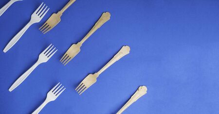 Organic bamboo disposable forks vs harmful plastic ones on trendy blue background. Environmentally...