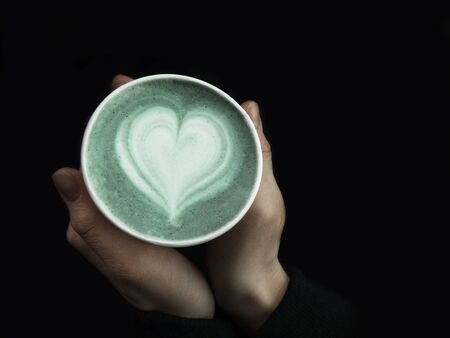 Female hands holding eco friendly cup of green matcha, Classic latte art. Empty place for text, copy space. Coffee addiction. Top viewの写真素材