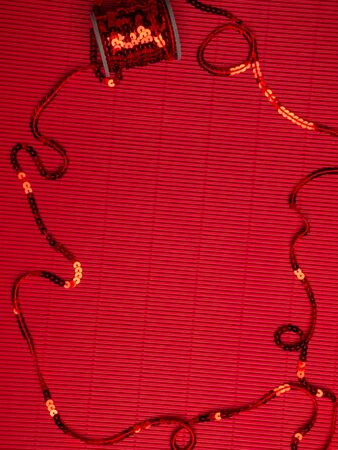 The spool of red sequins on a festive red corrugated background, decorating accessories used for embellishment of dresses. Card for greetingの写真素材